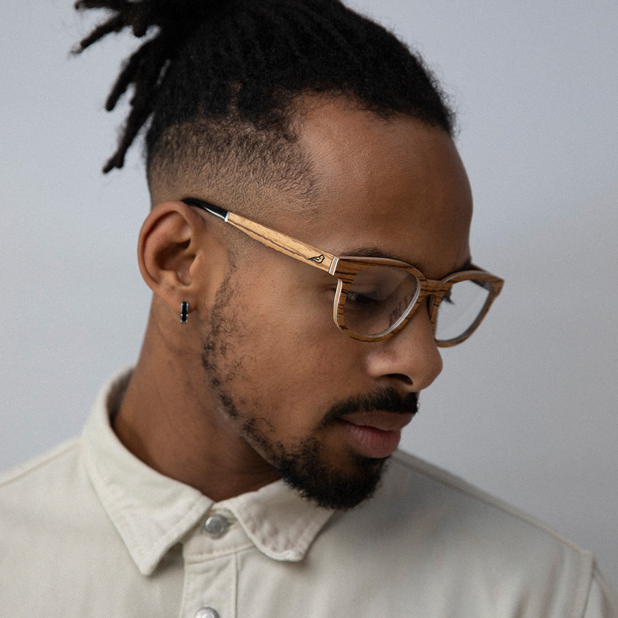 Black man wearing eco friendly glasses frame made with light wood looking down