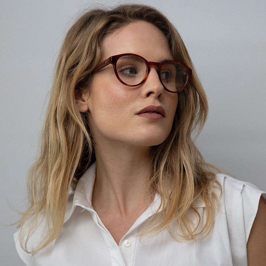 Women wearing red rimmed glasses made from sustainable acetate looking up 
