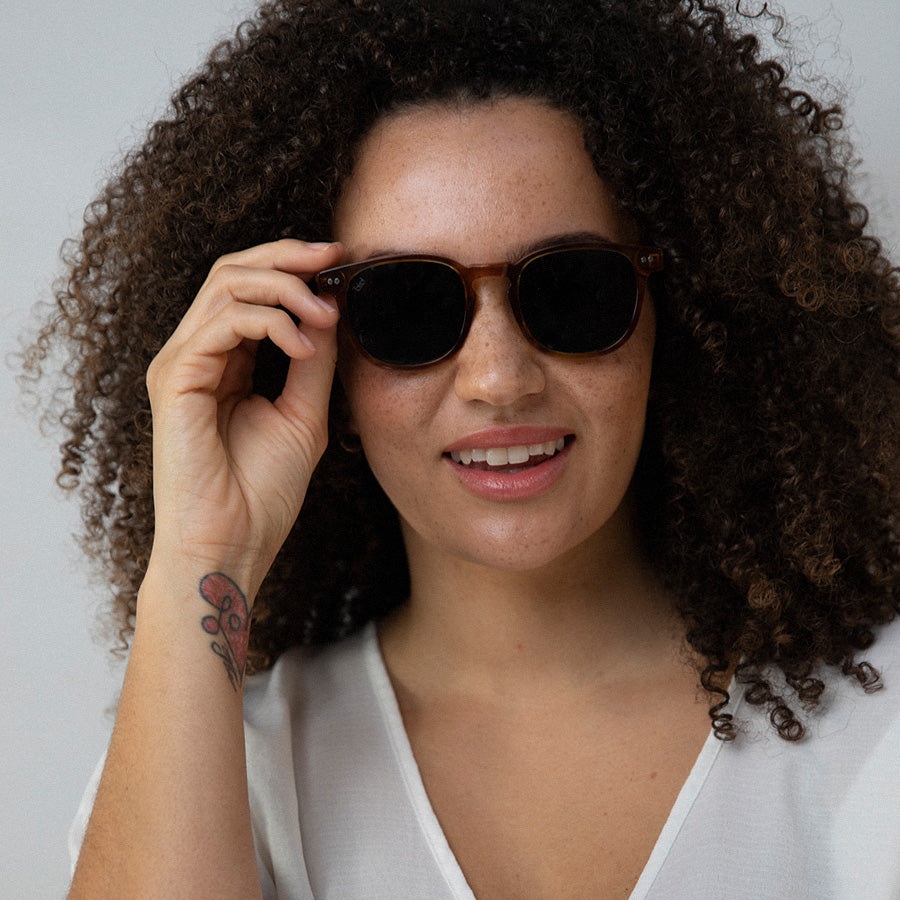 Black woman wearing small red frame sunglasses