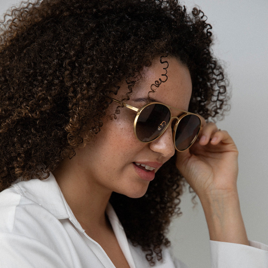 Black woman looking down wearing large aviator sunglasses with polarised lenses