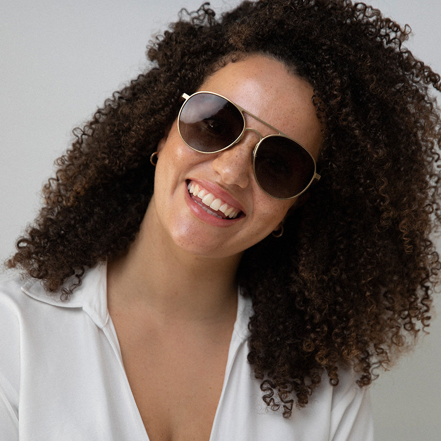 Black woman smiling wearing large aviator sunglasses with polarised lenses