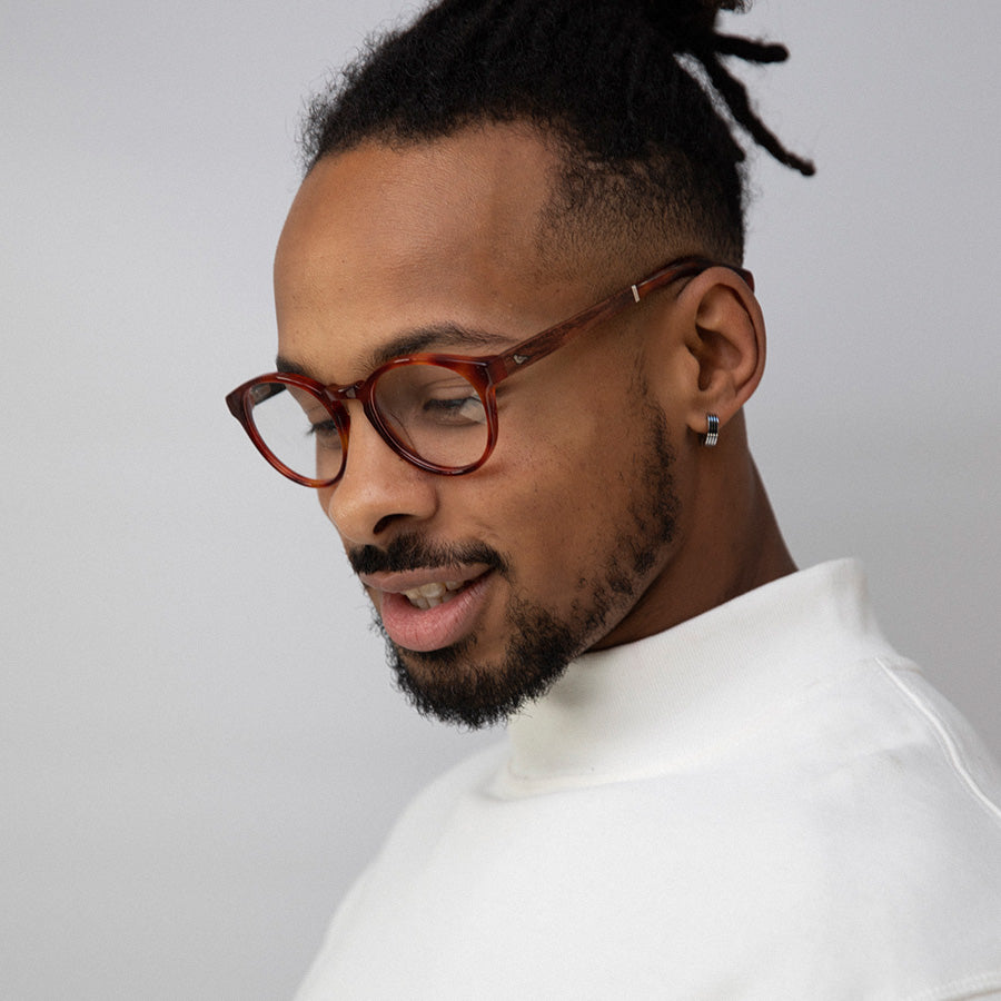 Black man looking down wearing red rimmed glasses made from sustainable acetate