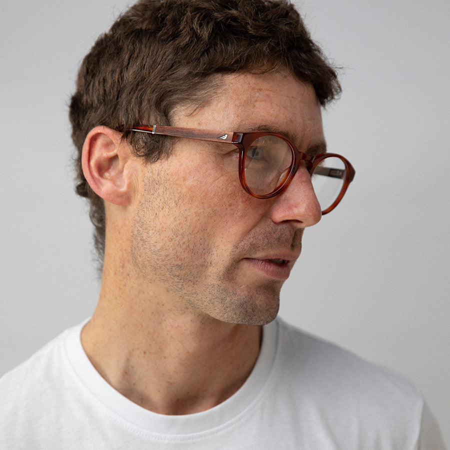 Man looking left wearing red rimmed glasses made from sustainable acetate
