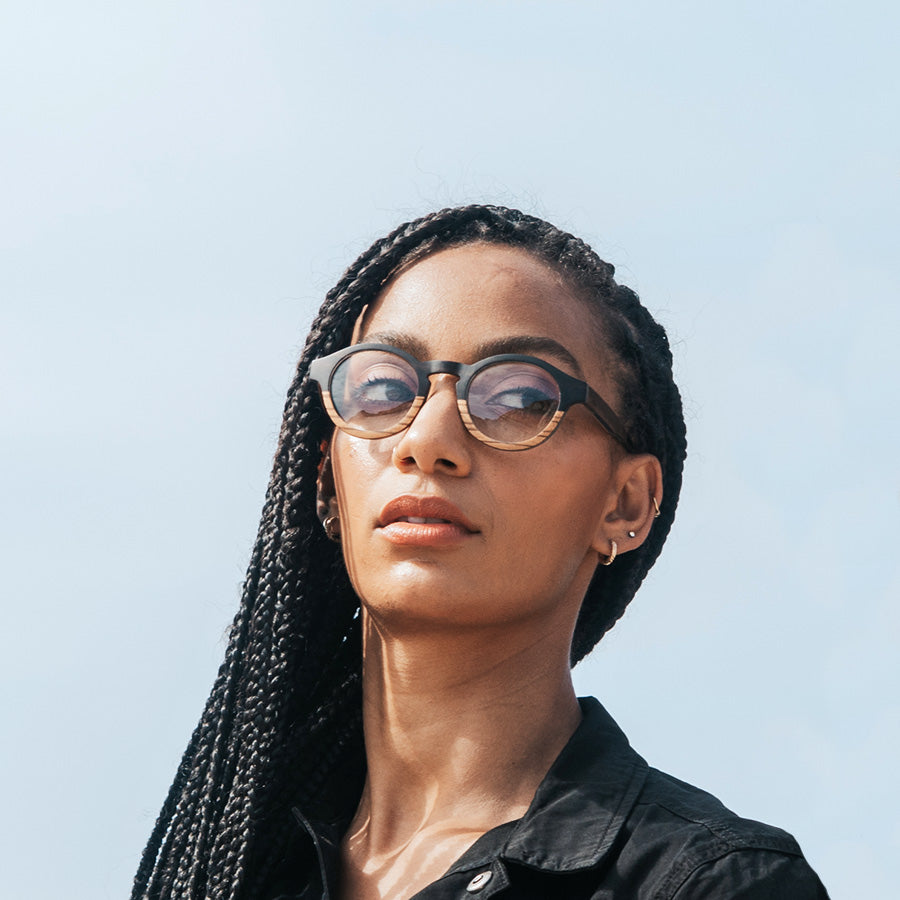 Black woman with blue sky wearing round wooden glasses for optical lenses 