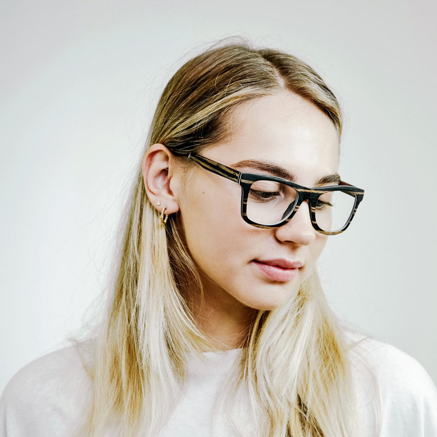 girl looking down wearing square wooden glasses 
